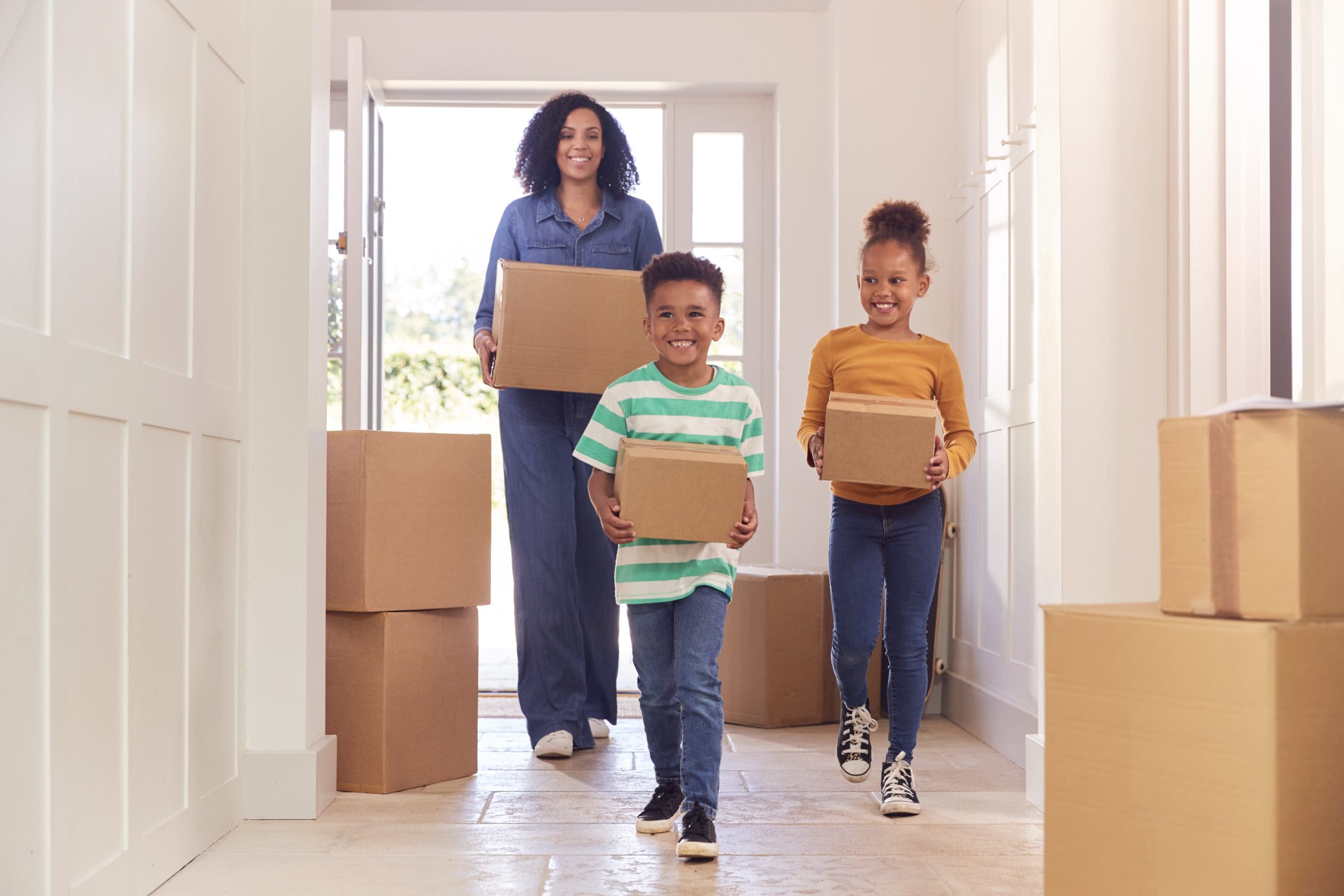 children helping their mother carry boxes into a new home on moving day