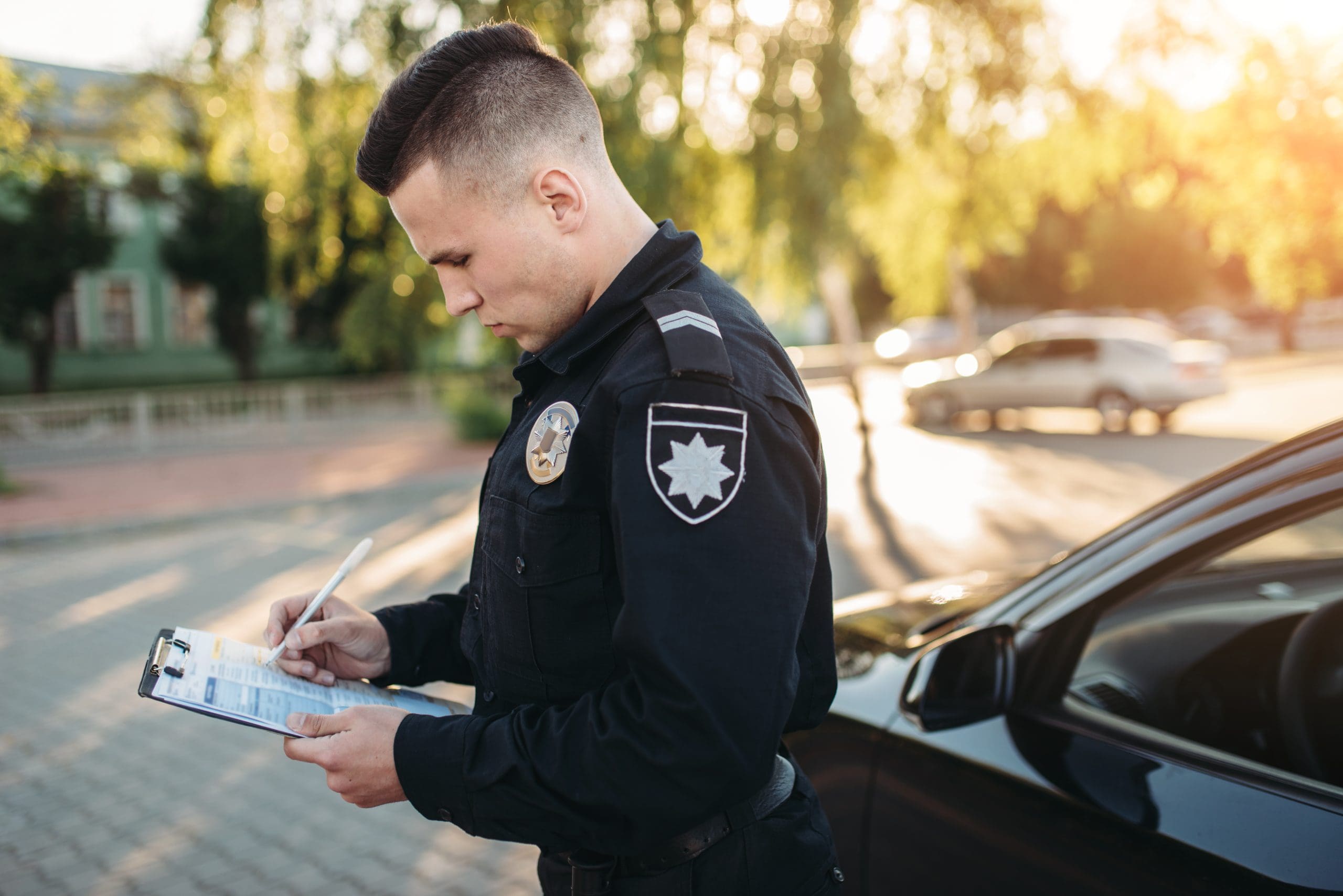 Young Man in Uniform Writes on Clipboard Outdoors